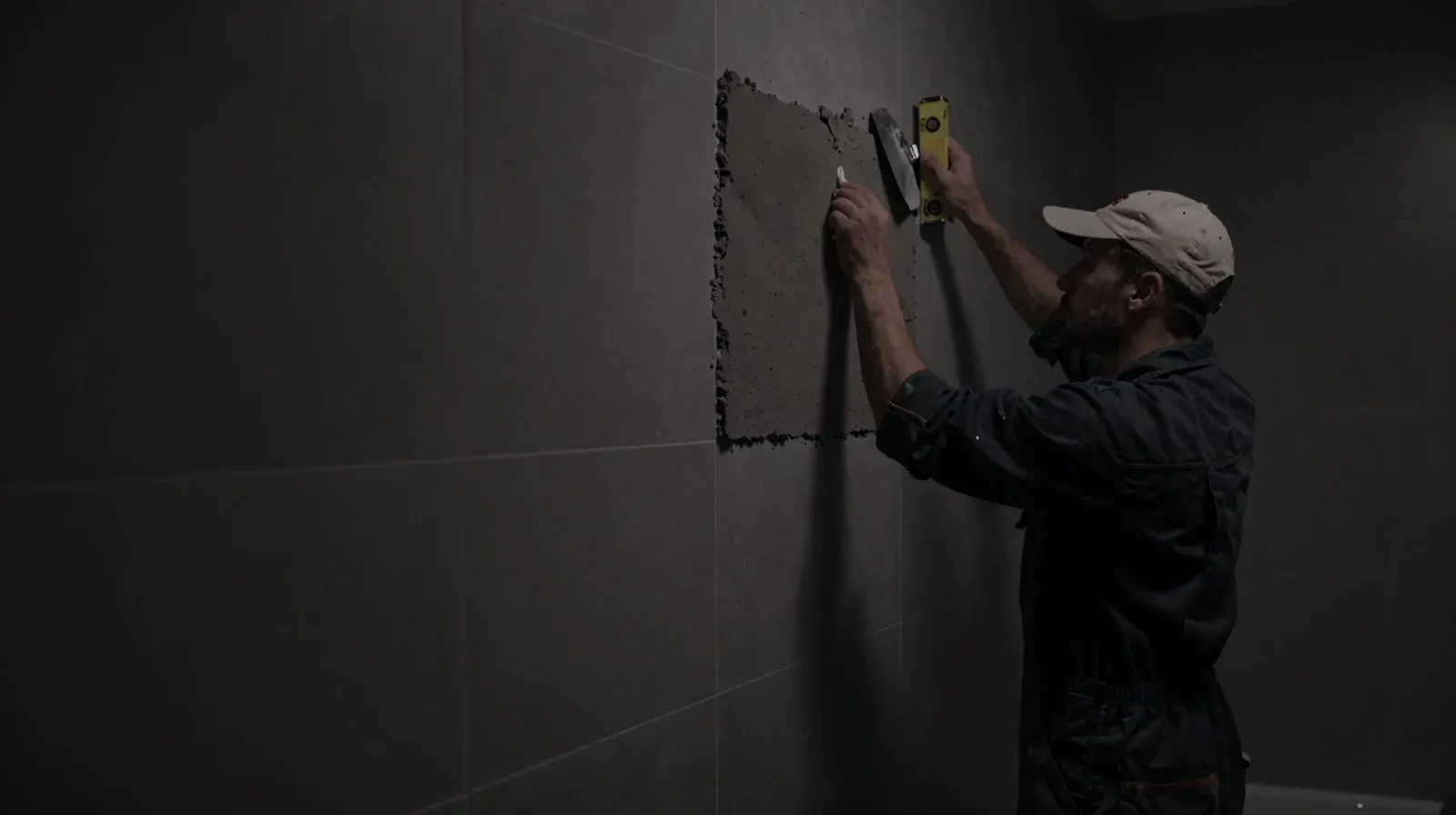 Fliesenleger verfugt eine Wand in einem neuen Bad